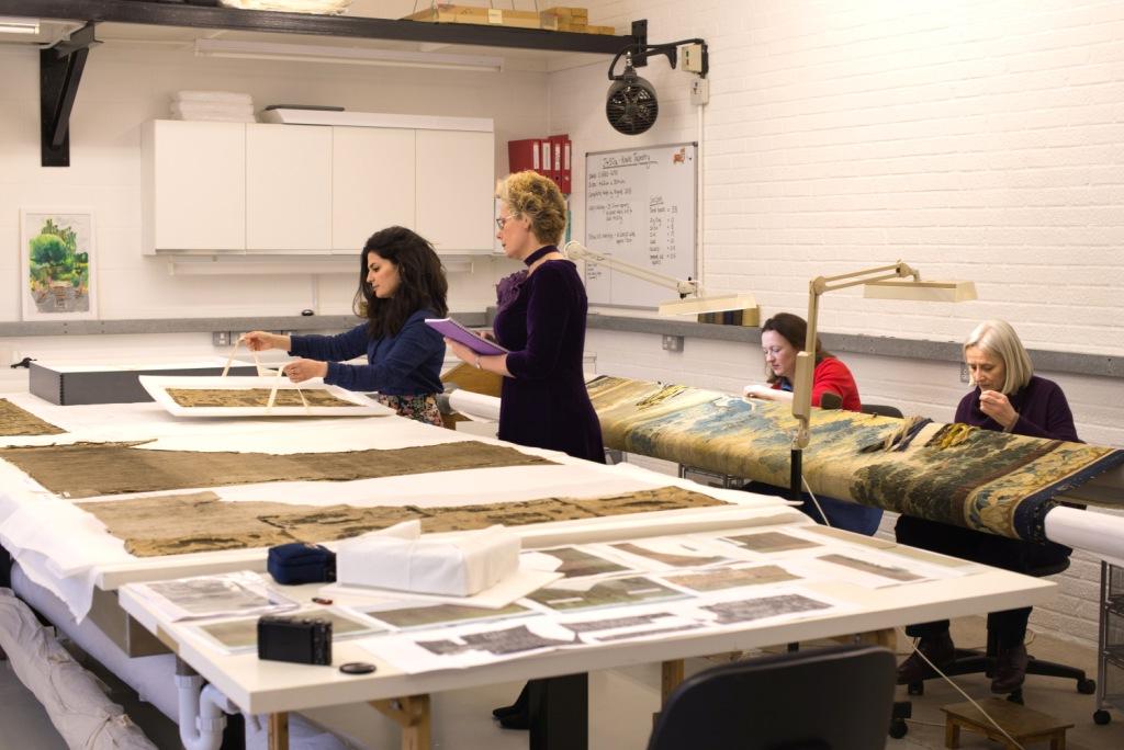 Maria and Claire at the table; Anna and May working at the Tapestry