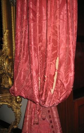 Showing damage to the silk on the folds of the curtain.